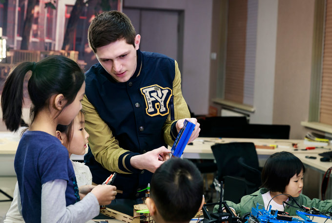 A young teacher helping students with an engineering task at Tsinglan School, which works with Huawei