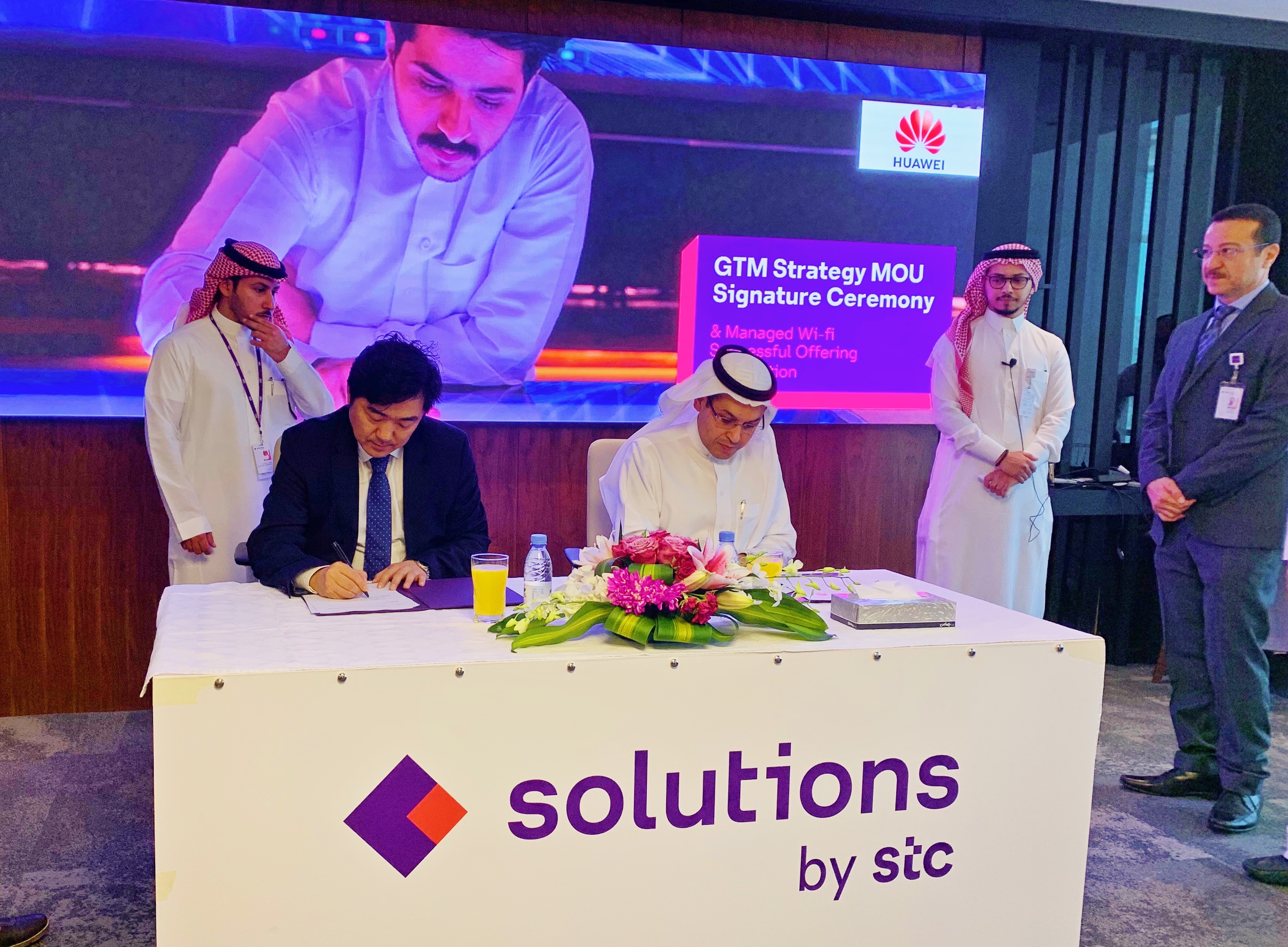 Seated representatives from the Saudi Telecom Company and Huawei sign a GTM MoU, a partnership called Solutions by STC