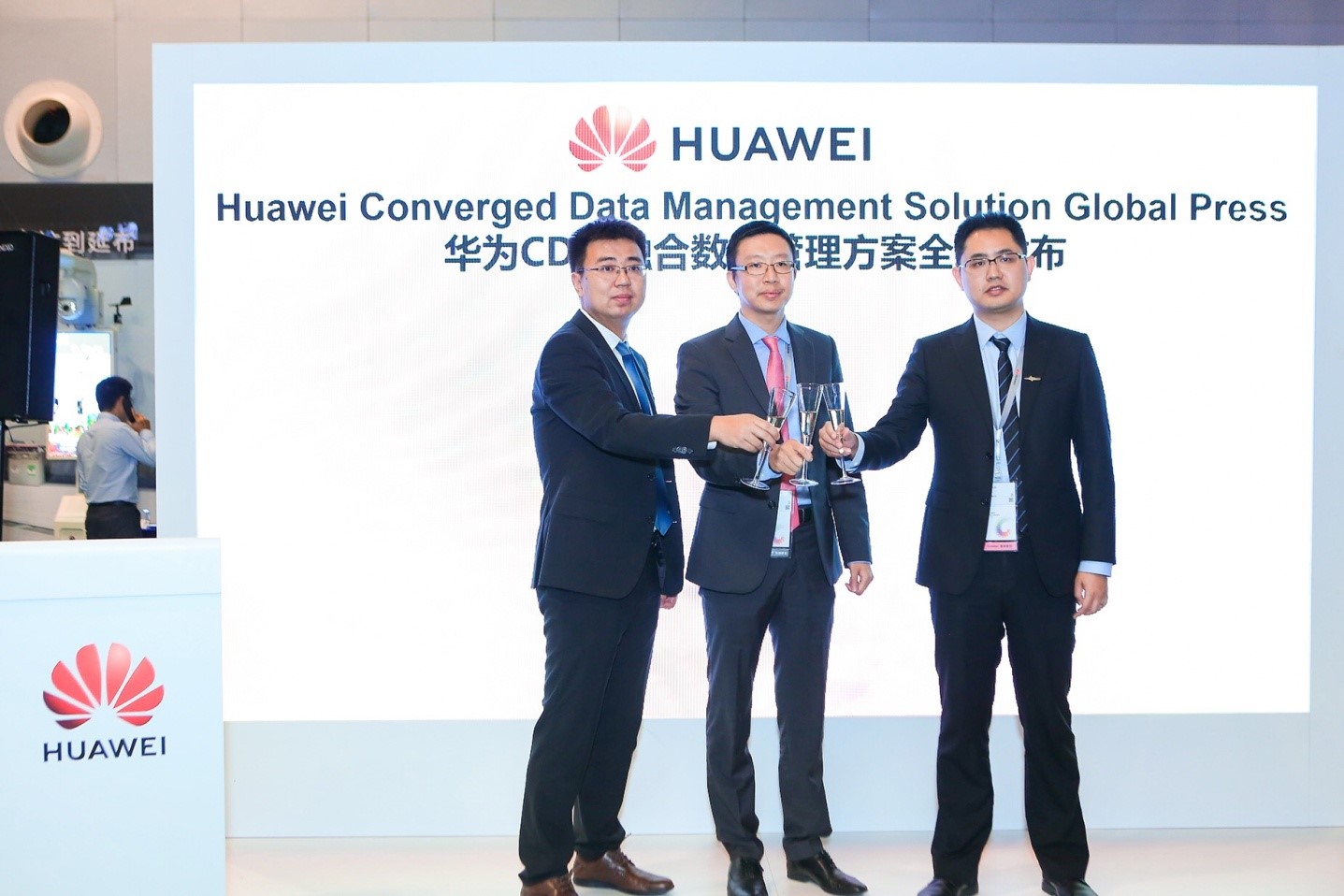 Three Huawei executives hold Champagne flutes, toasting the launch of the Converged Data Management (CDM) Solution