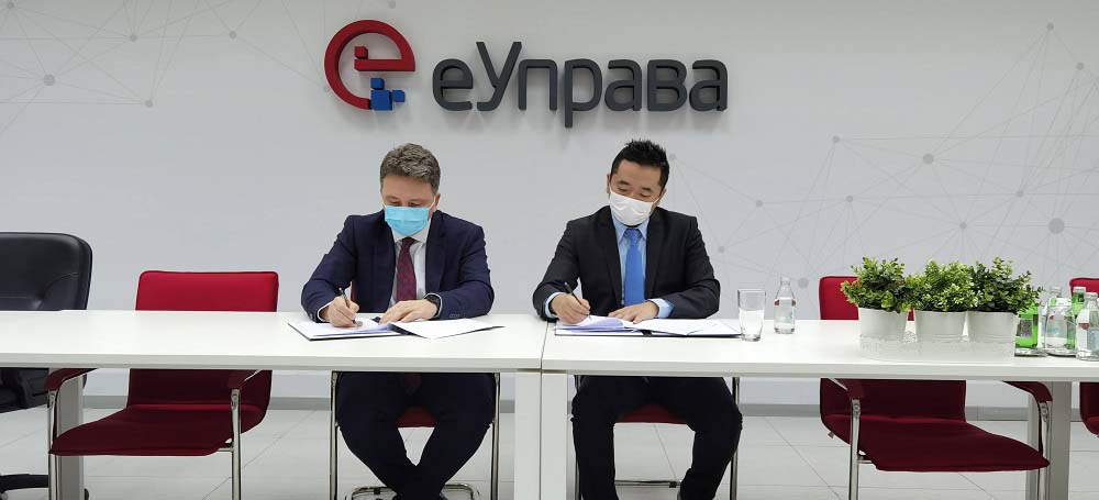 Seated representatives of Huawei and Serbia's Office for IT and e-government sign an agreement on the placement of equipment