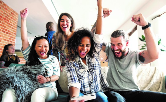 A team of four looking at a phone and cheering in an article on the gamification of learning by Huawei partner Microtest