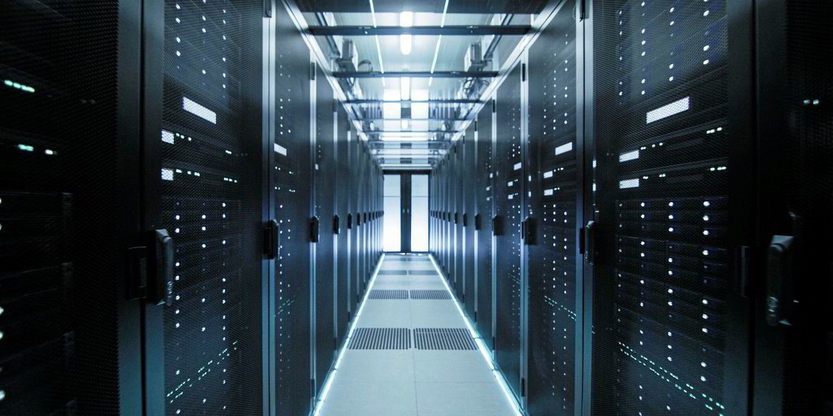 Looking down a data center corridor, with IT equipment racks on either side, representing the data-driven future of energy