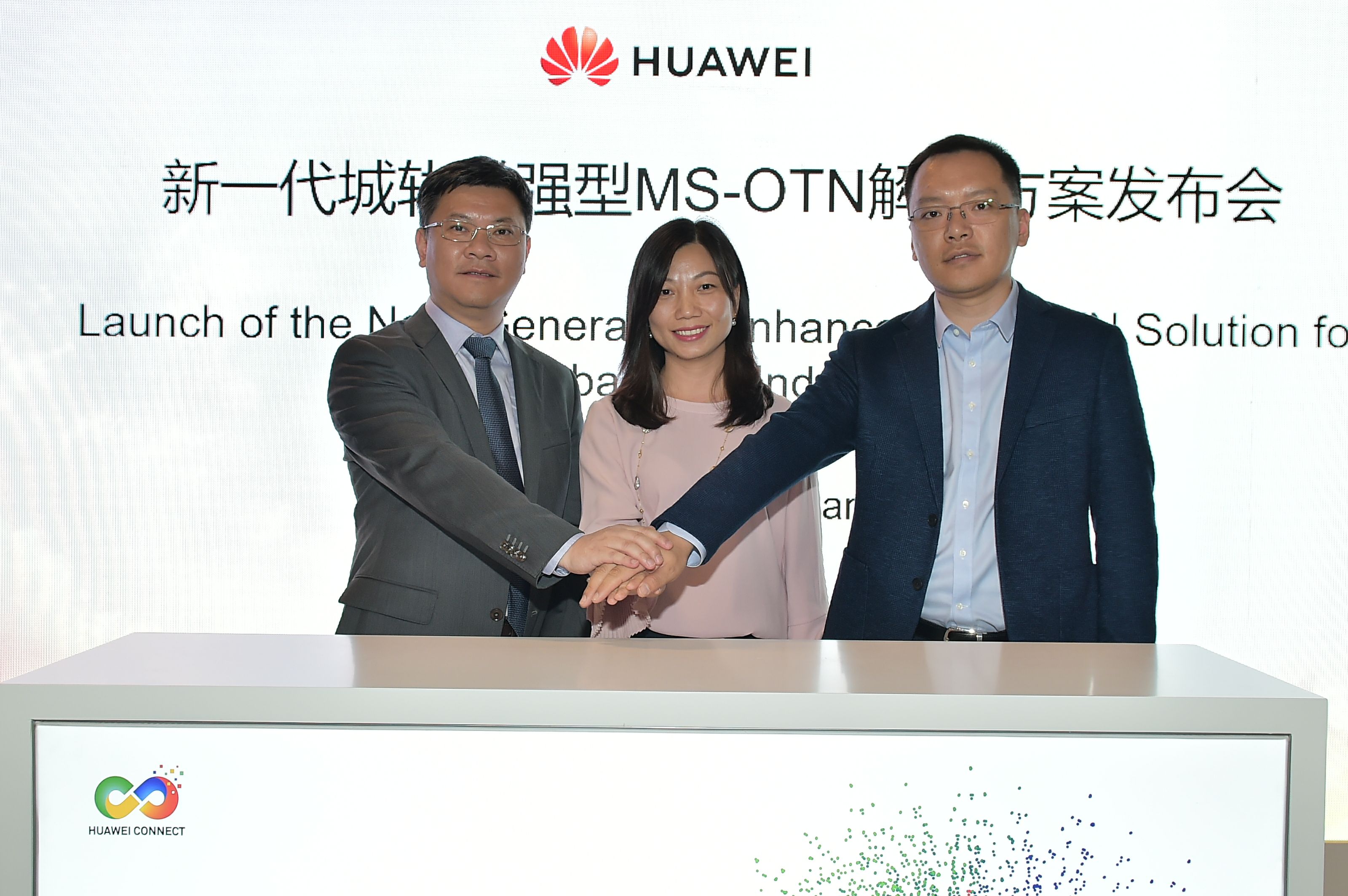 Three Huawei executives stack their hands on top of each other's at the launch of the Smart 100G Enhanced MS-OTN solution