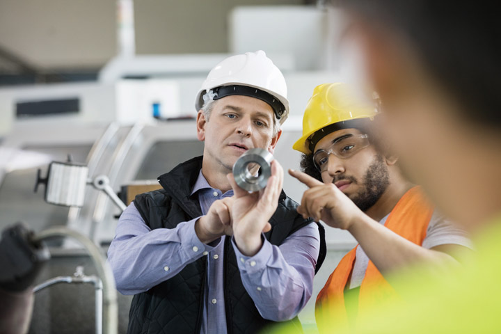 Two men are looking at a production part.